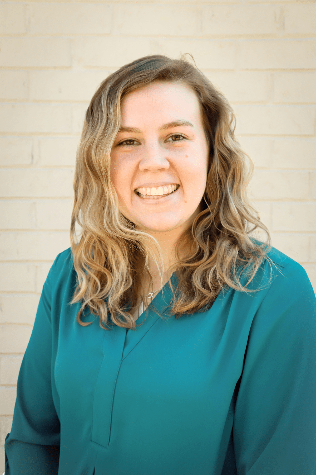Dana Powell, a white woman with dirty blonde hair wearing a teal blouse. She is smiling looking at the camera.