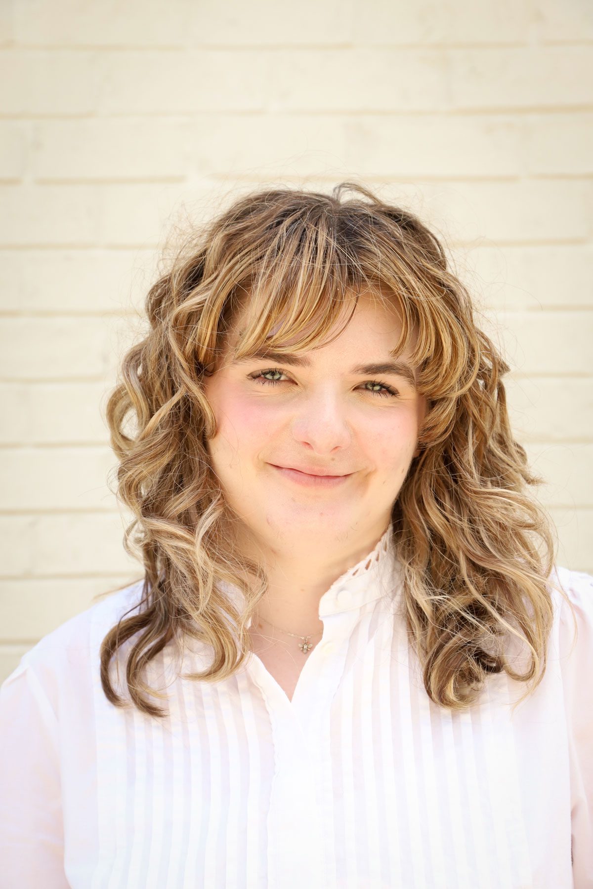 Kaeden Lutz, a white woman with dirty blonde hair and a white blouse. She is looking at the camera smiling.